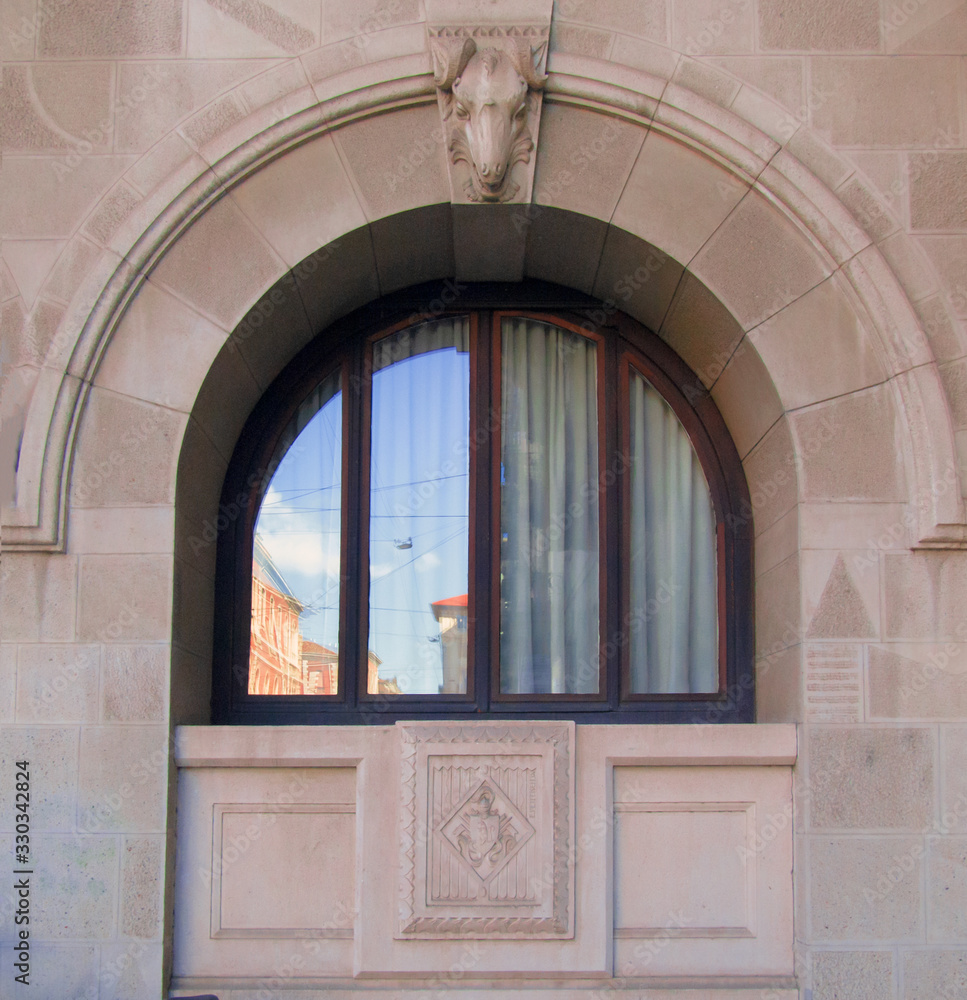 arched window of an ancient building inside which the blue sky is reflected