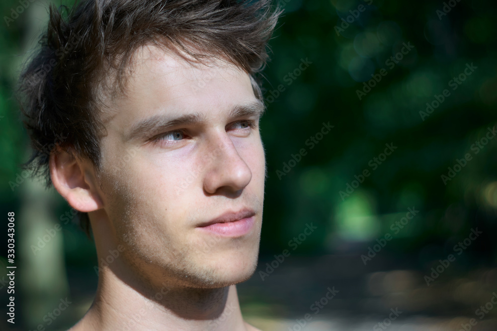 Pensive young man enjoying the warm sunlight on his face while gazing into the distance at sunset in summer. Pensive young man enjoying the warm sunlight on his face while gazing into the distance at sunset in summer.