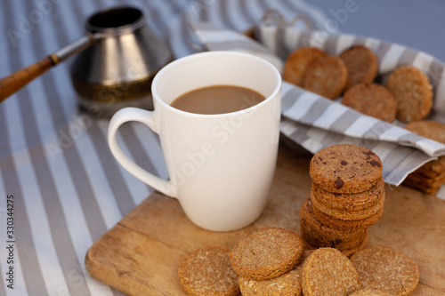 White cup with place for text. Breakfast is on the table. Cup with coffee and round homemade cookies. Mug with a drink and a snack. Mockup for designs. 