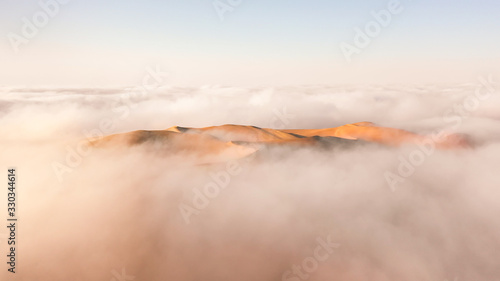Photography Aerial view of a massive sand dune surrounded by winter morning fog cloud in Empty Quarter