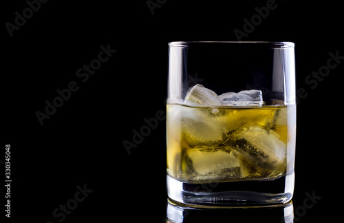 Tumbler glass with whiskey on black background