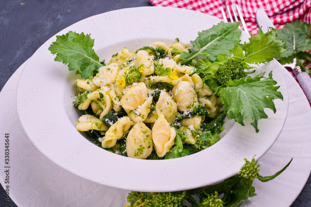 Cime di rapa pasta in a plate on with parmesan on table. Traditional food of the south of Italy, from Puglia. Rustic style photo. Copy space Cime di rapa pasta in a plate on with parmesan on table. Traditional food of the south of Italy, from Puglia. Rustic style photo. Copy space