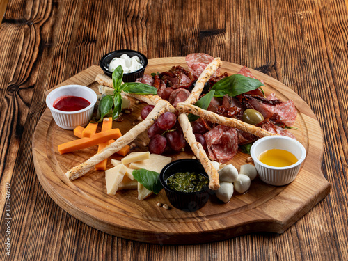 Wine platter with assorted snacks such as grissini, cheese, sliced meat and nuts on wooden board