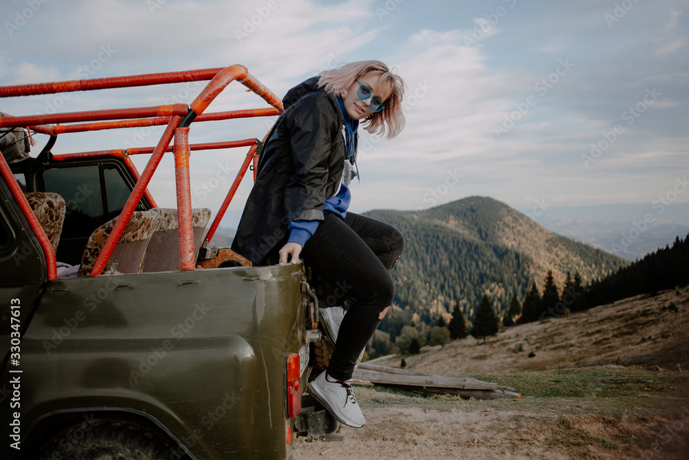 Obraz premium young woman on top of the mountain. extreme mountain jeep riding