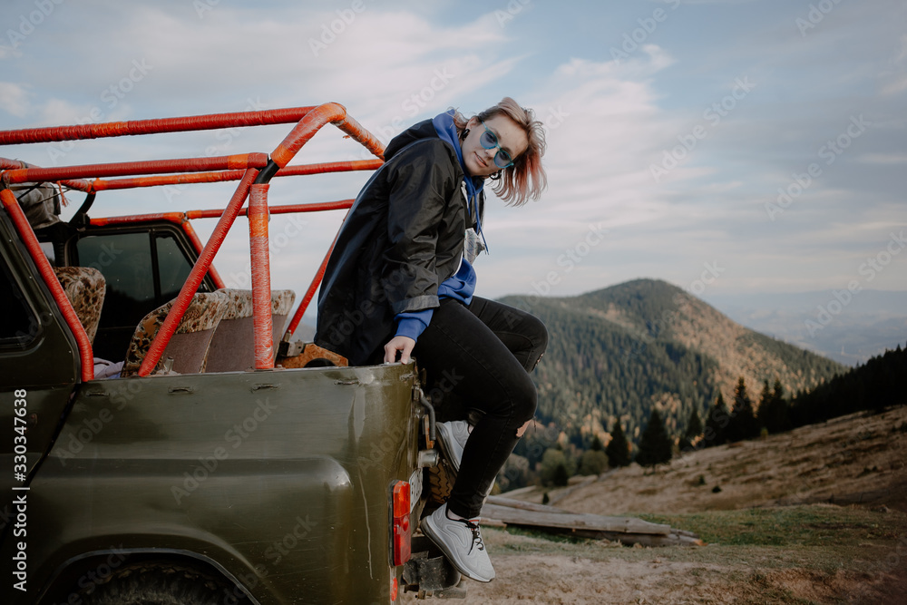 Obraz premium young woman on top of the mountain. extreme mountain jeep riding