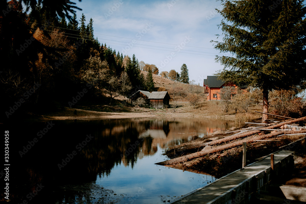 landscape with a cozy house by the lake in the mountains