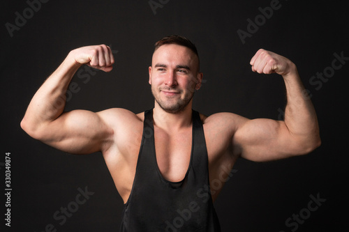 Young man showing biceps over black background