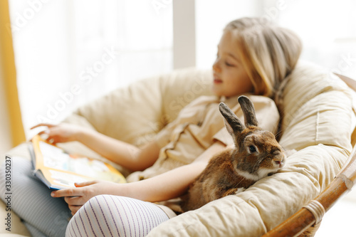 cute little girl study on the sofa in the company of rabbit 