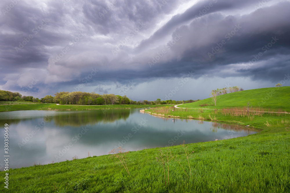 An approaching storm front creates a dramatic sky over a small lake on a spring afternoon in the Midwest.