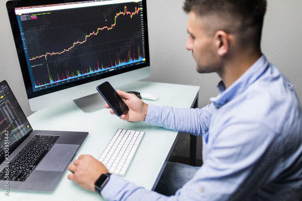 Agent trader man use phone and checking business stock data on computer in office room. Agent trader man use phone and checking business stock data on computer in office room.