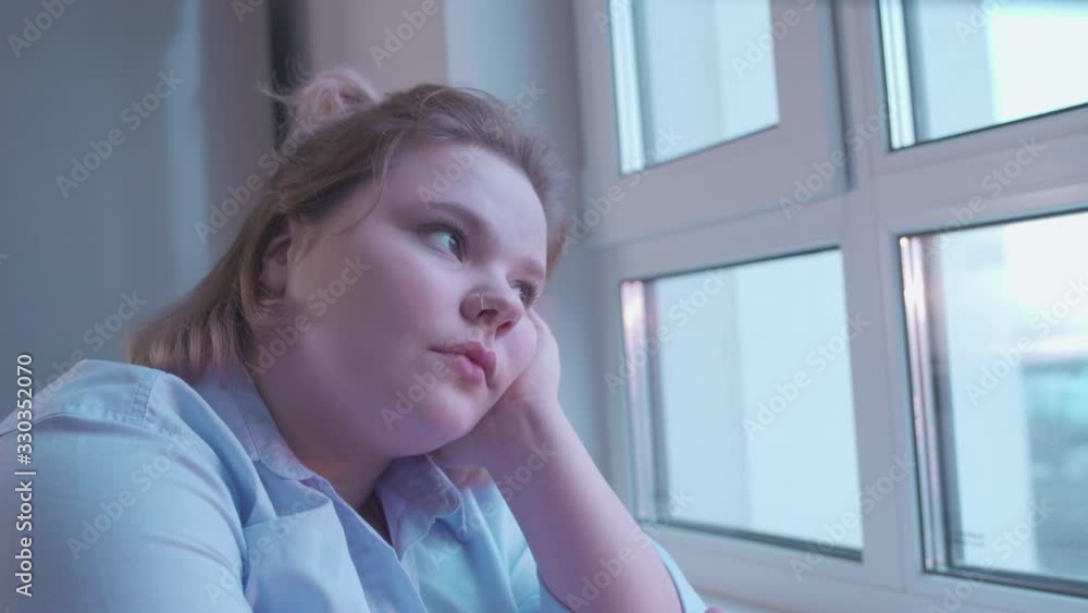 Depressed young woman looking in window, drug addict feeling lonely in rehab Depressed young woman looking in window, drug addict feeling lonely in rehab