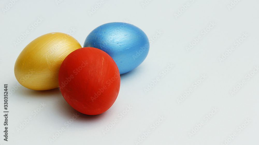 three colored Easter eggs blue red and gold close up on a white background three colored Easter eggs blue red and gold close up on a white background