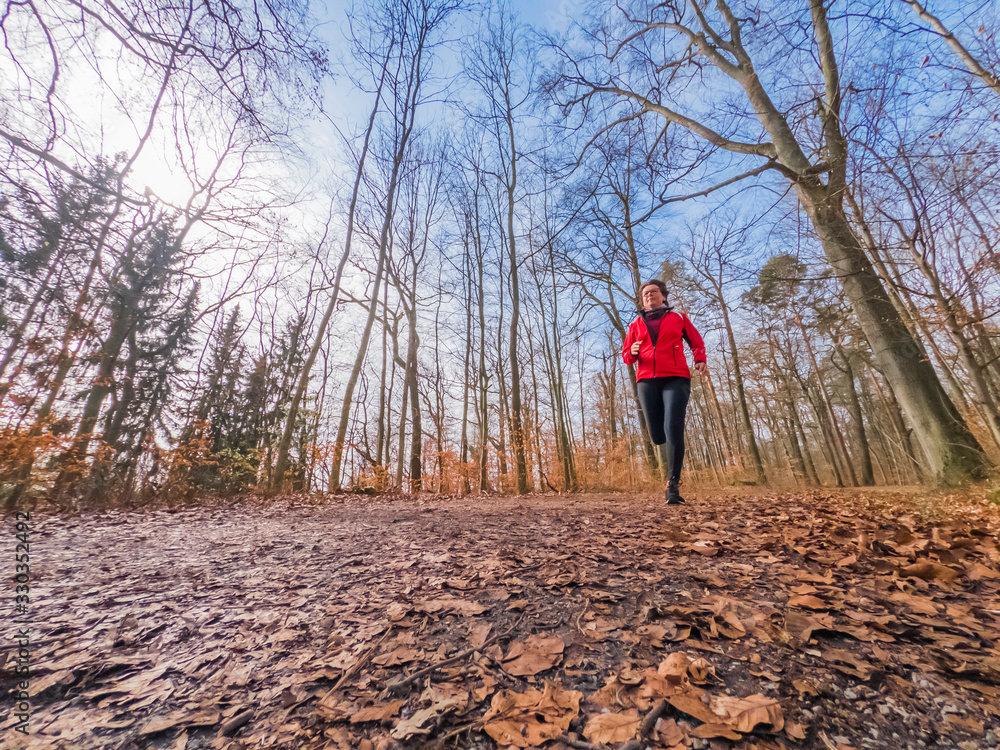 active senior woman running in the forest on a warm day in early spring active senior woman running in the forest on a warm day in early spring