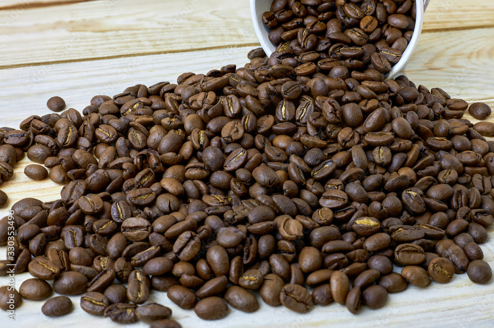 Fototapeta premium scattered coffee beans from paper cup on wooden table