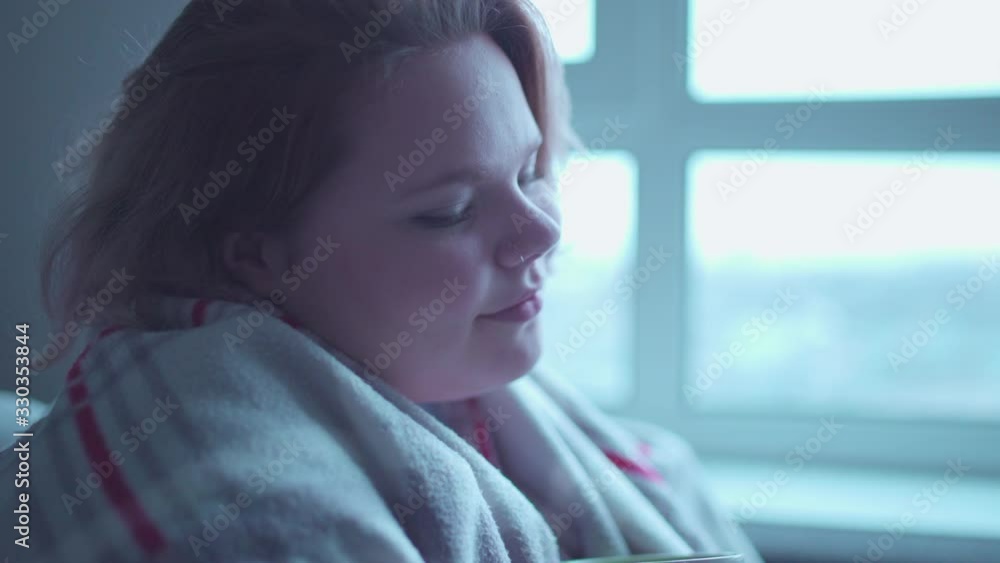 Happy girl smiling, covered with blanket and holding cup in hands, warm memories Happy girl smiling, covered with blanket and holding cup in hands, warm memories