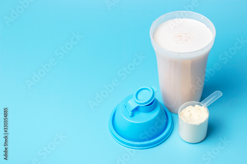 With a protein shake and a measuring spoon on blue background, copy space.
