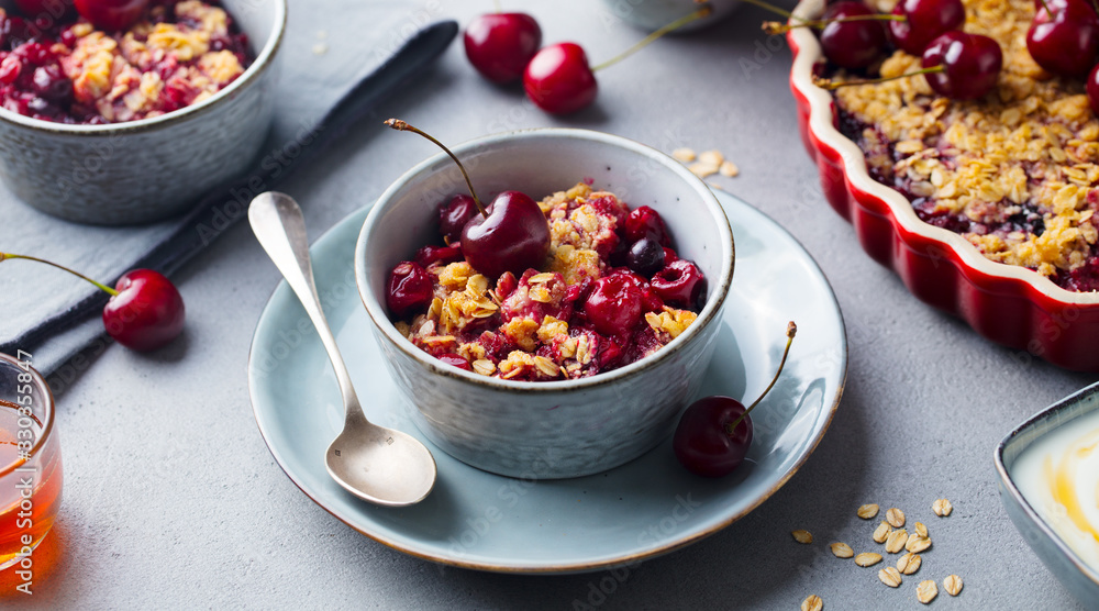 Healthy breakfast. Cherry, red berry crumble in bowl. Grey background. Close up. Healthy breakfast. Cherry, red berry crumble in bowl. Grey background. Close up.
