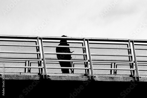 Man silhouette standing on bridge holding phone