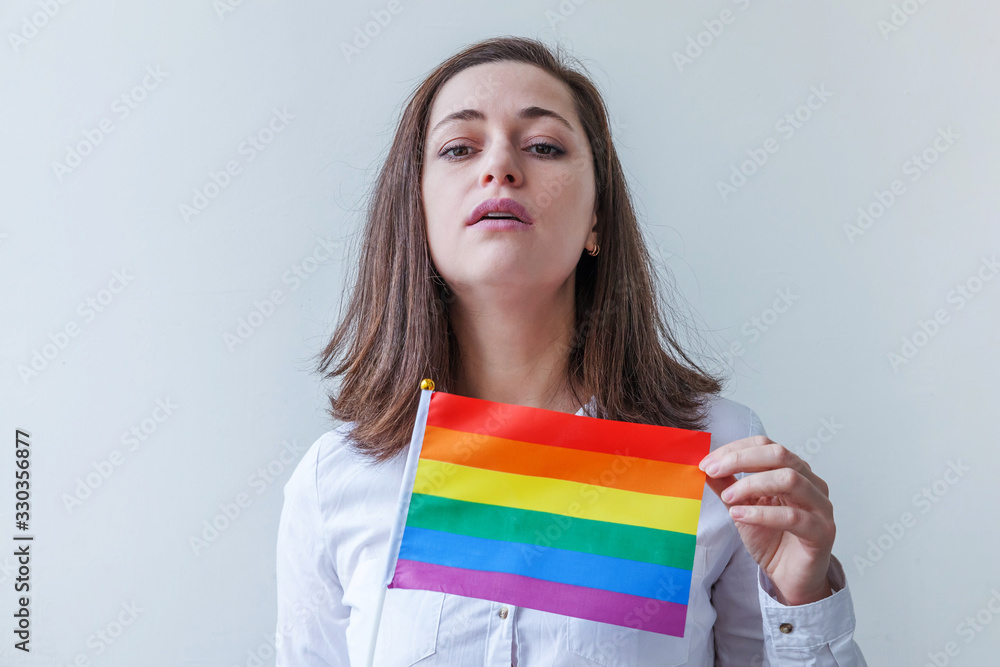 Beautiful caucasian lesbian girl with LGBT rainbow flag isolated on white background looking happy and excited. Young woman Gay Pride portrait. Equal rights for lgbtq community concept. Beautiful caucasian lesbian girl with LGBT rainbow flag isolated on white background looking happy and excited. Young woman Gay Pride portrait. Equal rights for lgbtq community concept.