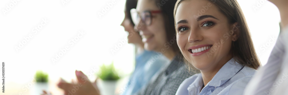 Portrait of smiling woman in classic shirt. Cheerful businesslady looking at camera with gladness. Top managers at seminar. People greeting someone and applauding - obrazy, fototapety, plakaty 