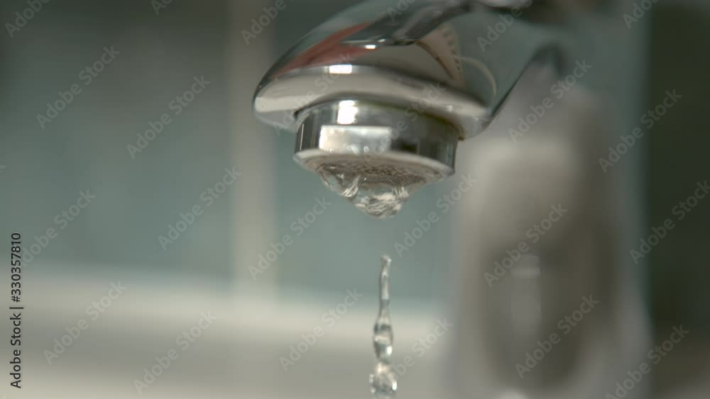 Slow motion, macro, DOF crystal clear water stops flowing from a shiny metal bathroom faucet Slow motion, macro, DOF crystal clear water stops flowing from a shiny metal bathroom faucet