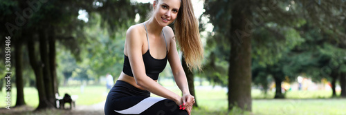 Portrait of beautiful sportswoman in sportswear doing sports in green park. Wonderful bodybuilder looking at camera with gladness. Fitness and sport concept