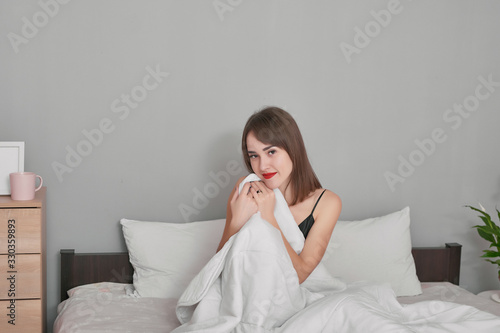 Morning, relaxation, people concept - happy young woman in bed at home bedroom under blanket. Girl in pajamas on bed. Cozy and good morning. Breakfast in bed. Hotel room. Woman woke up in morning