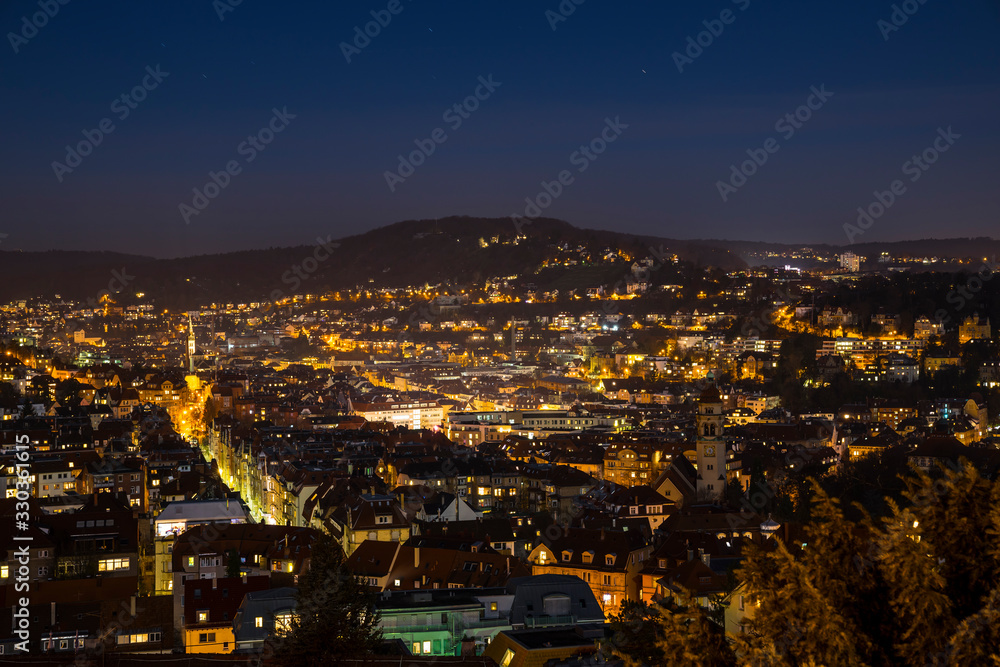 Germany, Magical aerial view above illuminated skyline of city stuttgart houses in basin in clear winter night with starry sky and lots of lights