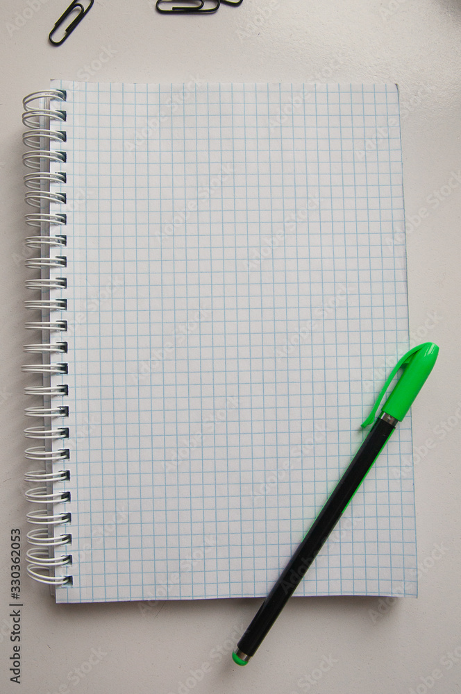 on the table a Notepad with a pen and paper clips top view on the table a Notepad with a pen and paper clips top view