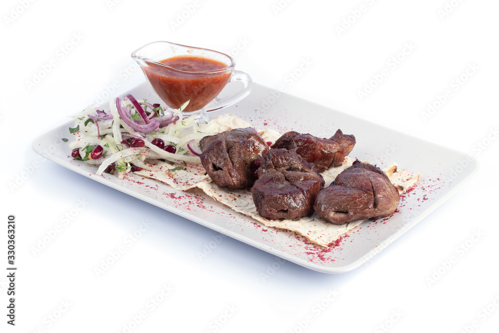 Lamb shish kebab with fresh vegetables and red sauce on a white plate for menu and web Lamb shish kebab with fresh vegetables and red sauce on a white plate for menu and web