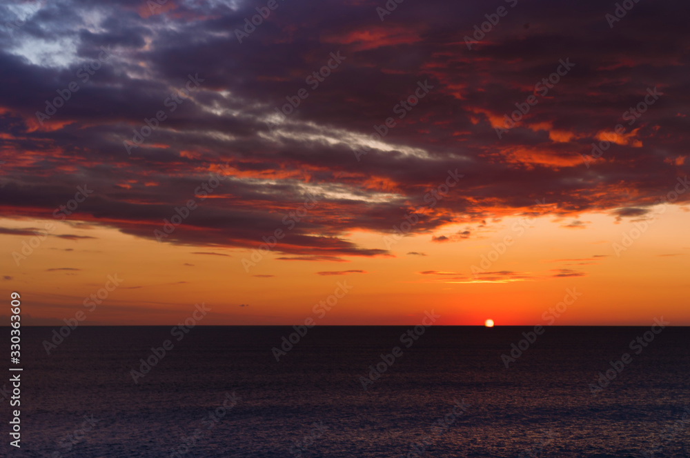 Sunset on the sea with beautiful colors and some clouds in Cadiz
