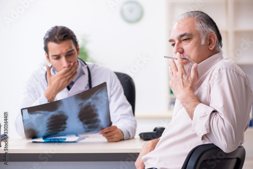 Принти на полотні Young male doctor and old patient in antismoking concept