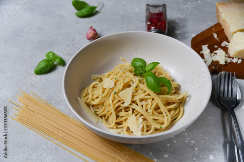 Spaghetti pasta with parmesan cheese and basil in a white plate on a light background top view. gluten free spaghetti recipe homemade pasta. classic Italian cuisine. selective focus