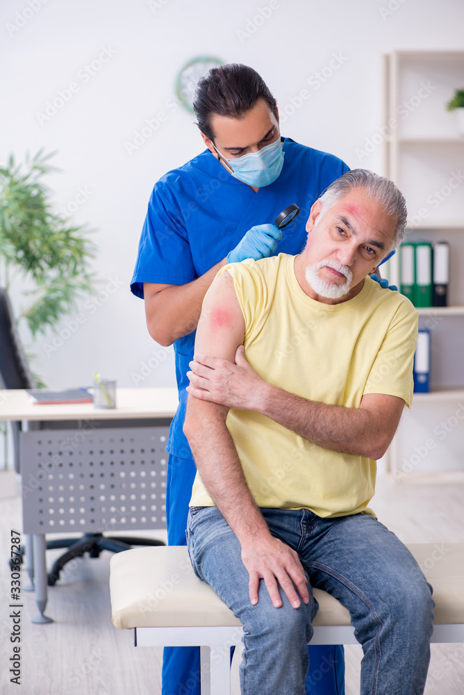 Obraz premium Injured old man visiting young male doctor traumatologist