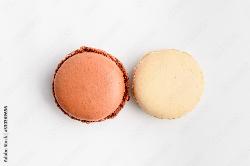 Top view of two sweet vivid brown chocolate and white vanilla French macaron isolated on white background, tasty French dessert on a table