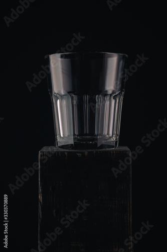 Empty glass for whiskey, brandy or bubon, old fashion type, copy space, selective focus on black background and wooden table. photo