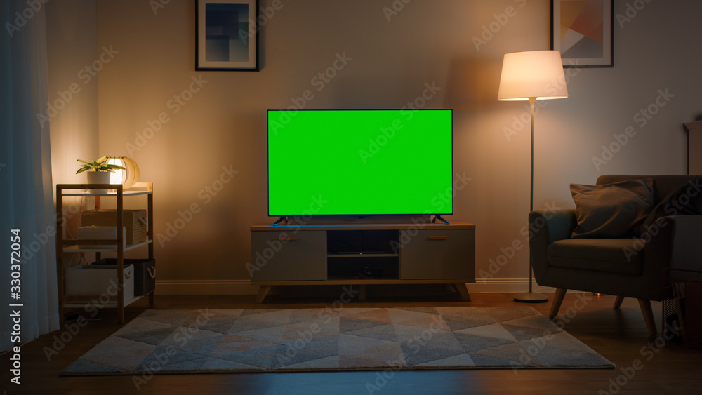 Shot of a TV with Horizontal Green Screen Mock Up. Cozy Evening Living