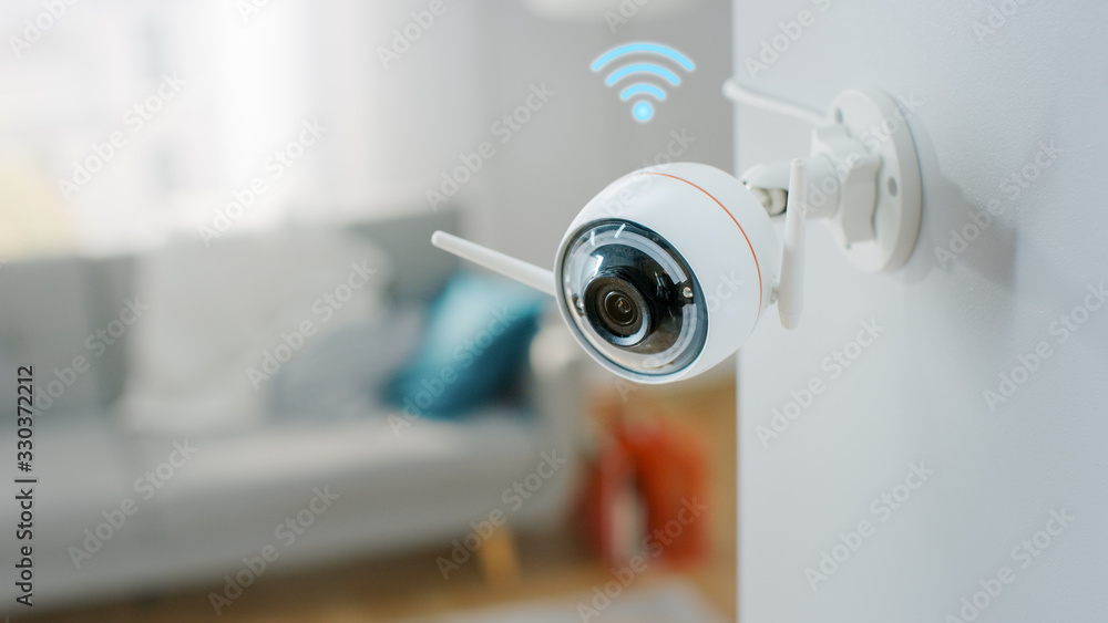 Close Up Object Shot of a Modern Wi-Fi Surveillance Camera with Two Antennas on a White Wall in a Cozy Apartment Has Wi-Fi Icon Above it. Close Up Object Shot of a Modern Wi-Fi Surveillance Camera with Two Antennas on a White Wall in a Cozy Apartment Has Wi-Fi Icon Above it.
