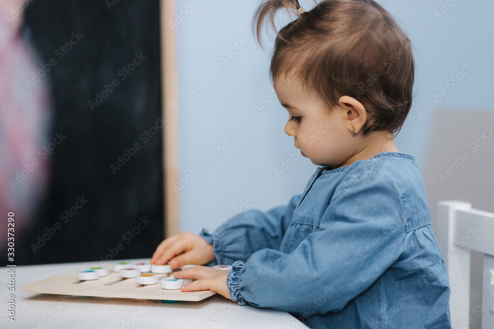 Little baby in kindergarden play. Baby girl in blue jeans shirt. Cute little baby in nursery Little baby in kindergarden play. Baby girl in blue jeans shirt. Cute little baby in nursery