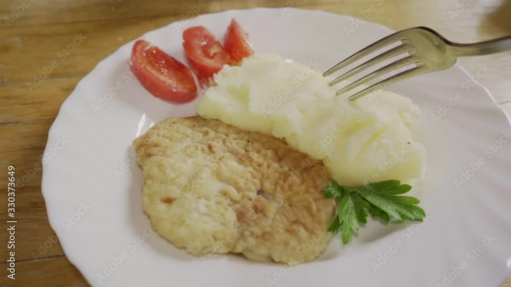 Someone eats mashed potatoes with chop and fresh vegetables in first person view Someone eats mashed potatoes with chop and fresh vegetables in first person view