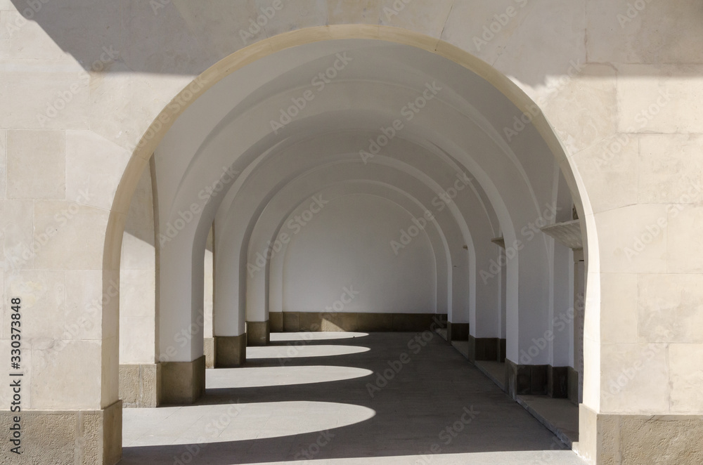Hallway to a building with arches and shadow play