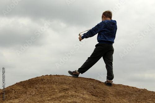 A boy shooting by slingshot from a hill down.