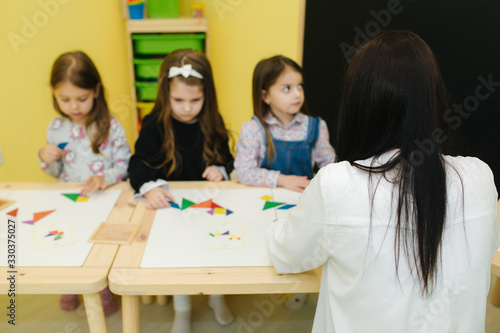 Children play with different figures on the table. Girls and boys in kindergarden