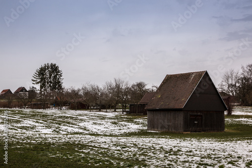 Brown cabin on the icy green field in winter photo