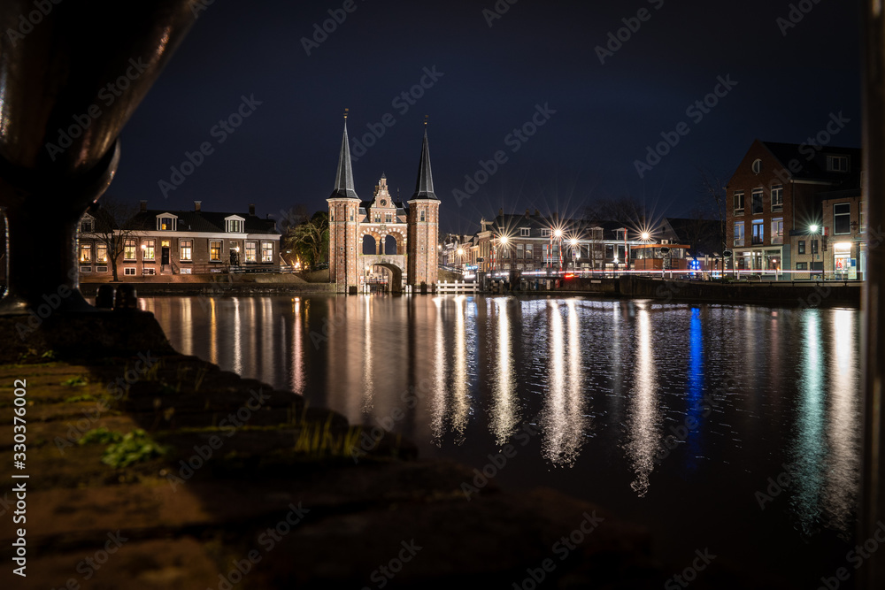 The famous historical 'Waterpoort' in the city of Sneek at night with reflections in the canal - Sneek, Friesland, The Netherlands