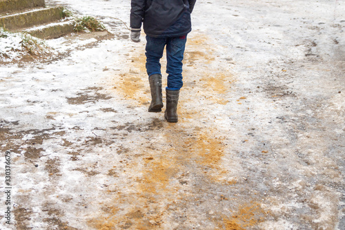 Sanding of streets in icy conditions in the winter. A man walks on the road with ice.