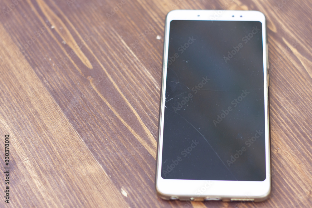 a fallen white smartphone with a crack on the screen. a fallen white smartphone with a crack on the screen.