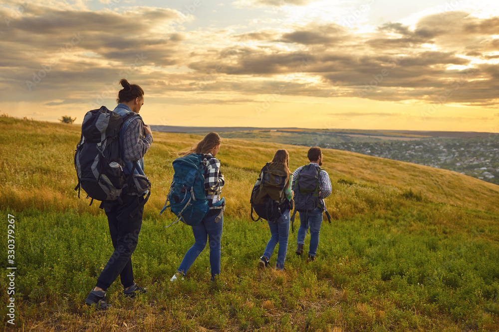 Group of people trekking with backpacks walking on the hill .