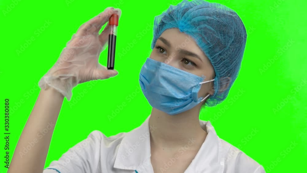 Portrait of young female doctor with blood test capsule. Exploring new virus strain. Green chromakey background for keying. Portrait of young female doctor with blood test capsule. Exploring new virus strain. Green chromakey background for keying.