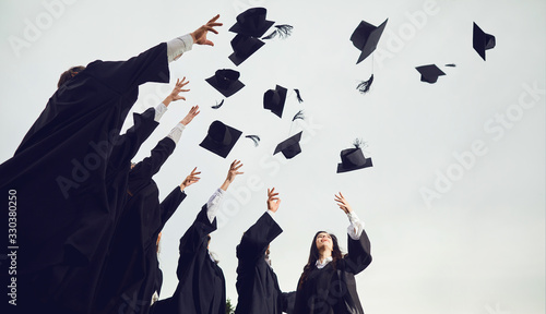 Bild auf Leinwand A group of graduates throws hats up into the sky.